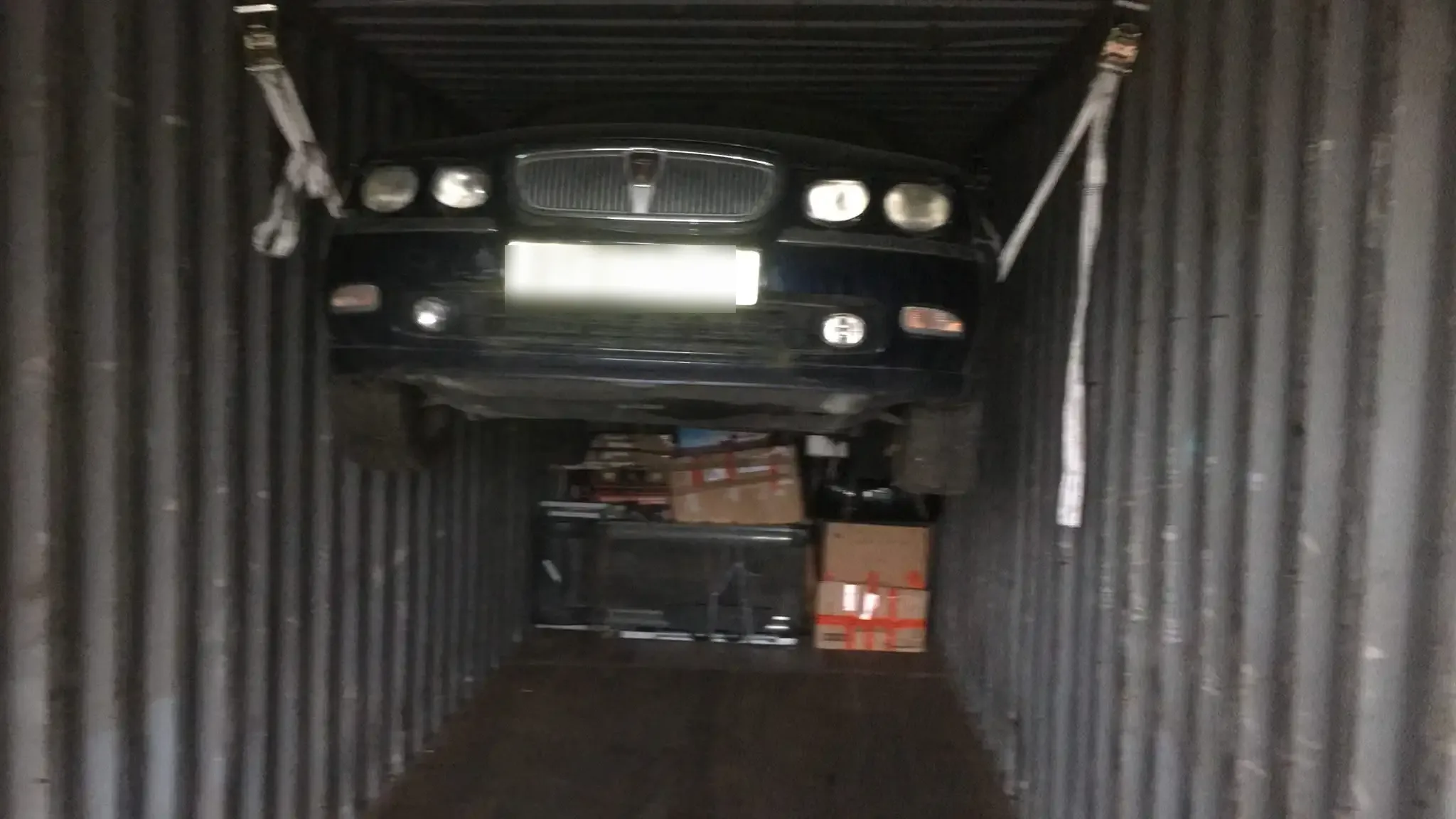 Car raised and secured above boxed cargo inside a container for UK to Africa import and export