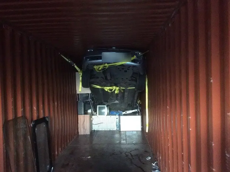 Car suspended and lashed inside an empty shipping container ready for loading cargo beneath