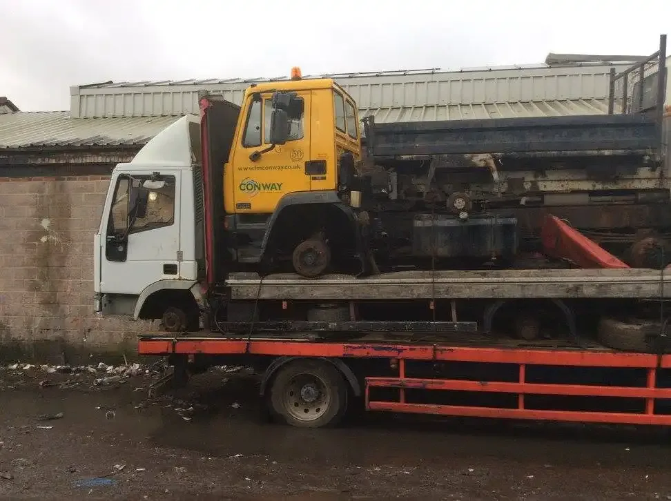 Recovered trucks loaded on a flatbed trailer for vehicle transport by Rolats Services